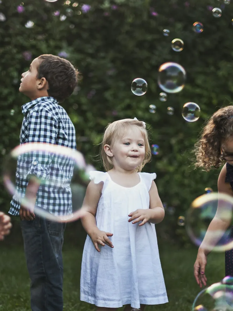 Kinder spielen im Garten mit Seifenblasen